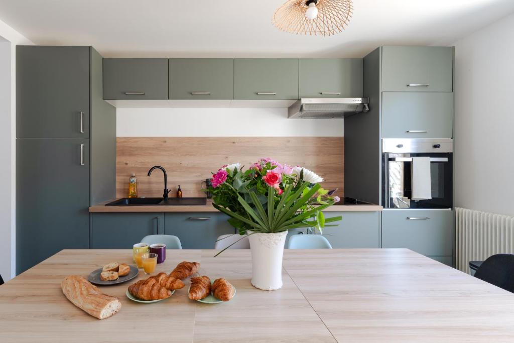 a kitchen with a table with bread and flowers at L'impasse - Maison avec jardin proche du centre in Rouen