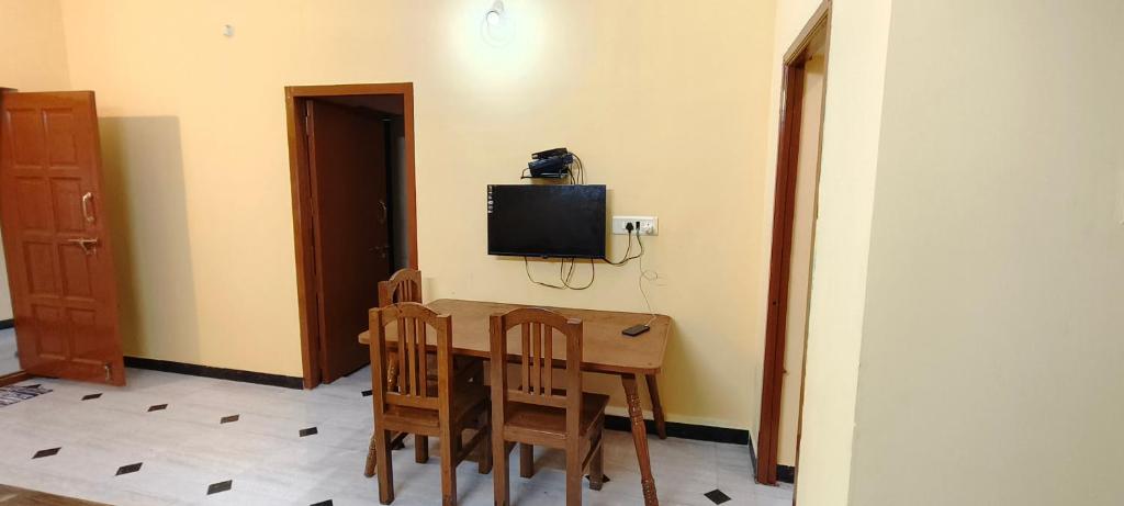 a room with a table and chairs and a television at SP resort inn in Yercaud