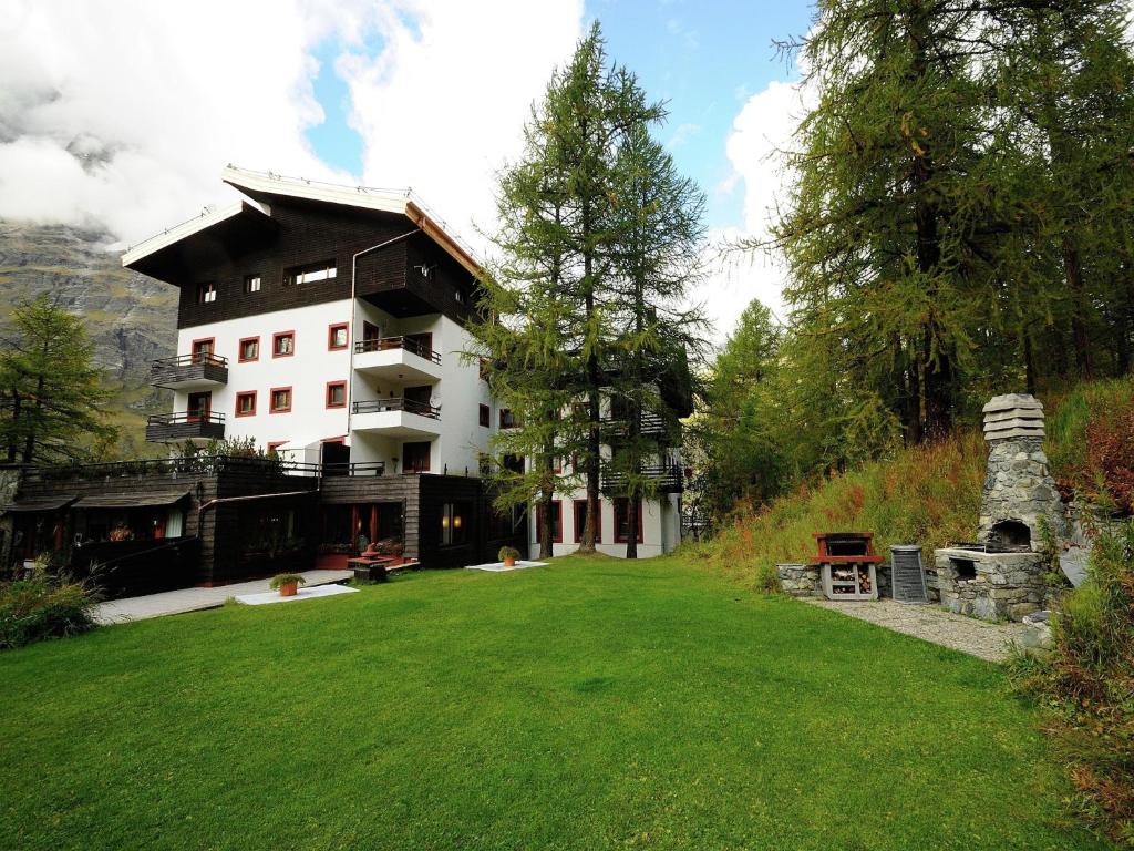 a large building on a hill with a green yard at Ski, stay, and savour Aosta Valley in Breuil-Cervinia