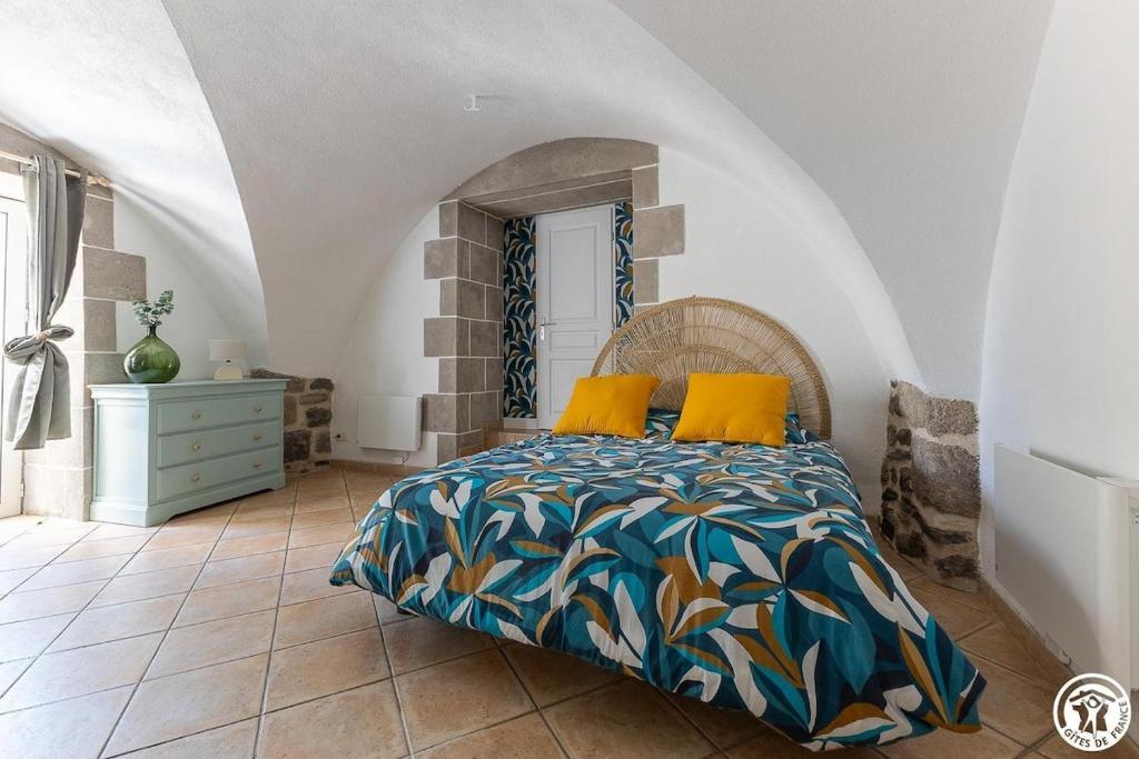 a bedroom with a bed with yellow pillows on it at Gîte La Clé de Voûte in Aydat