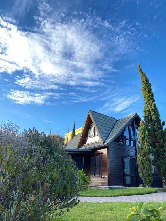 a house with a blue sky and clouds at Acogedora Casa de Madera con piscina in Güimar