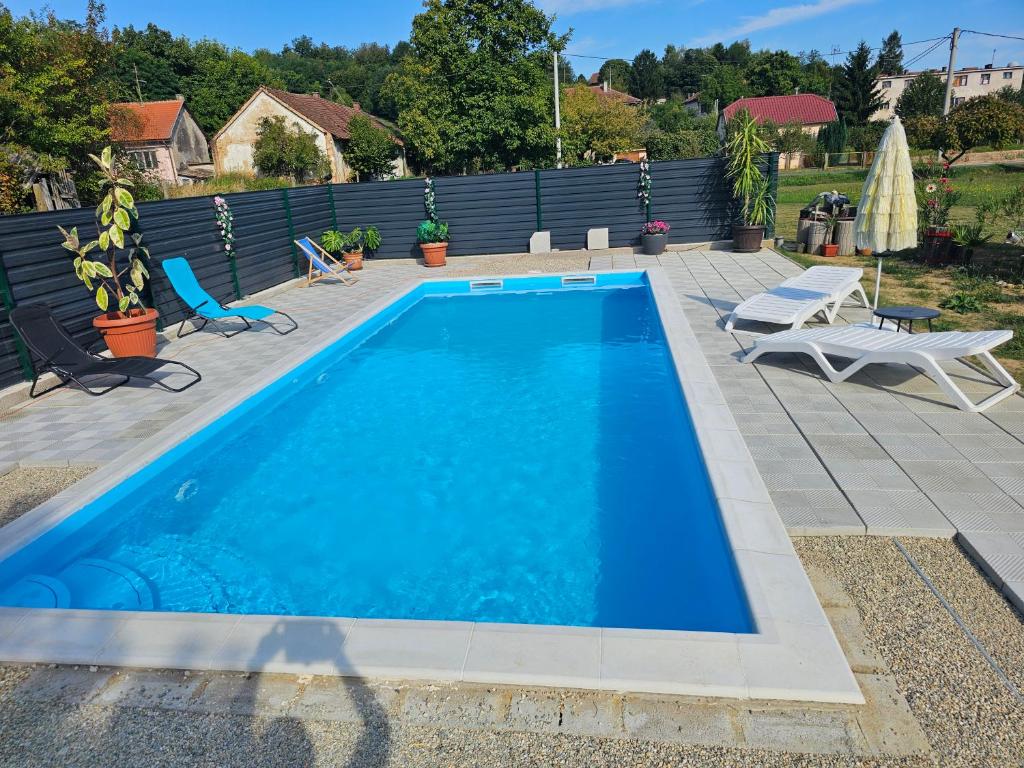 a blue swimming pool with two chairs and a fence at OPG Lukaček in Glogovac