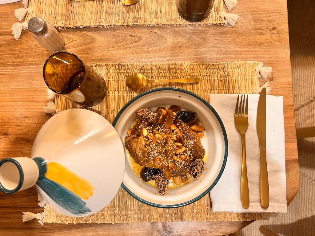 une table avec une assiette de nourriture et un verre de vin dans l'établissement Riad Jardin de Malia, à Marrakech