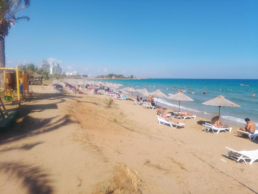una playa con muchas personas sentadas en sillas y sombrillas en Cesar Resort Didius, en Trikomo
