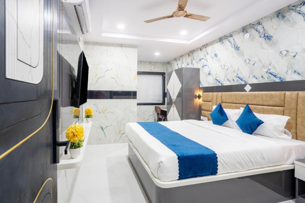 a bedroom with a bed with blue and white pillows at Sunrise Hotel Shamshabad in Hyderabad