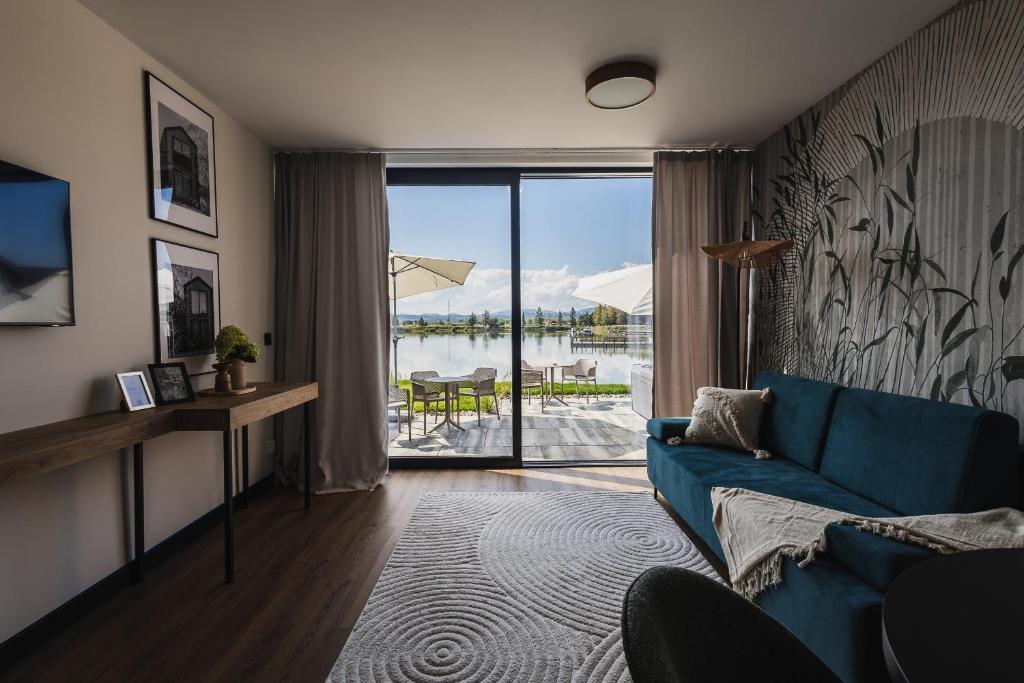 a living room with a blue couch and a view at Apartamenty Na Stawach 24 in Stary Sącz
