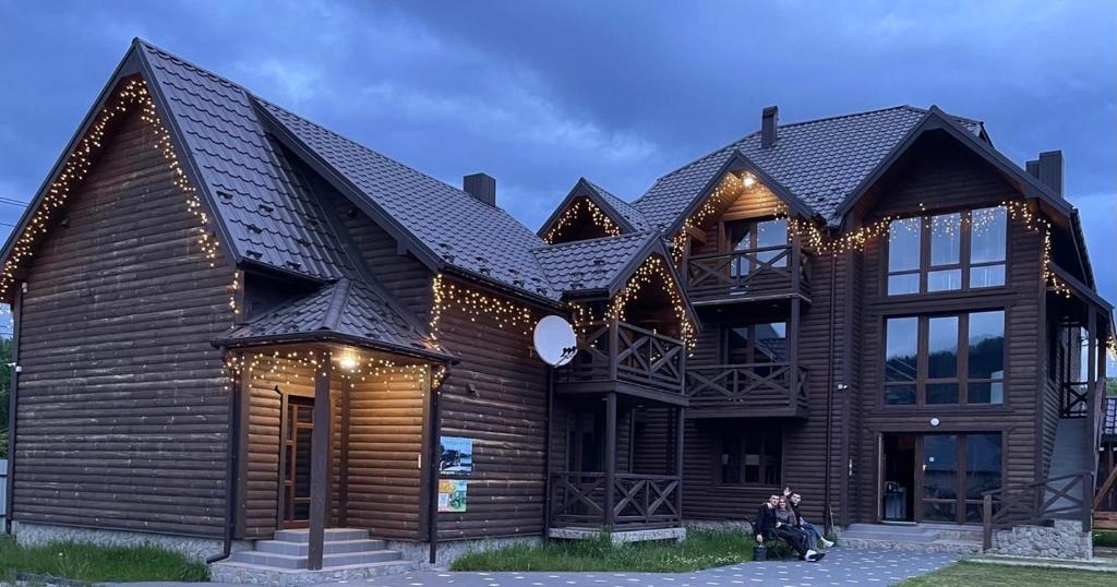 a woman sitting in front of a wooden house at Українка in Mykulychyn