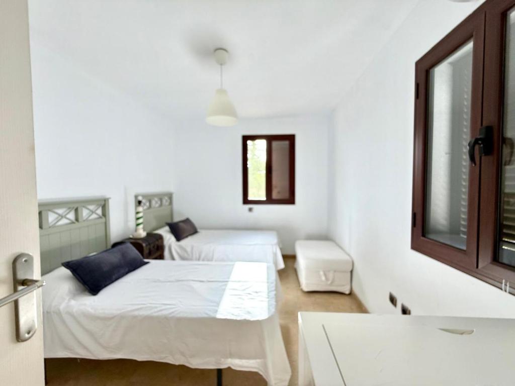 Un dormitorio blanco con dos camas y una ventana. en Atuaire Home Sevilla, en Mairena del Aljarafe