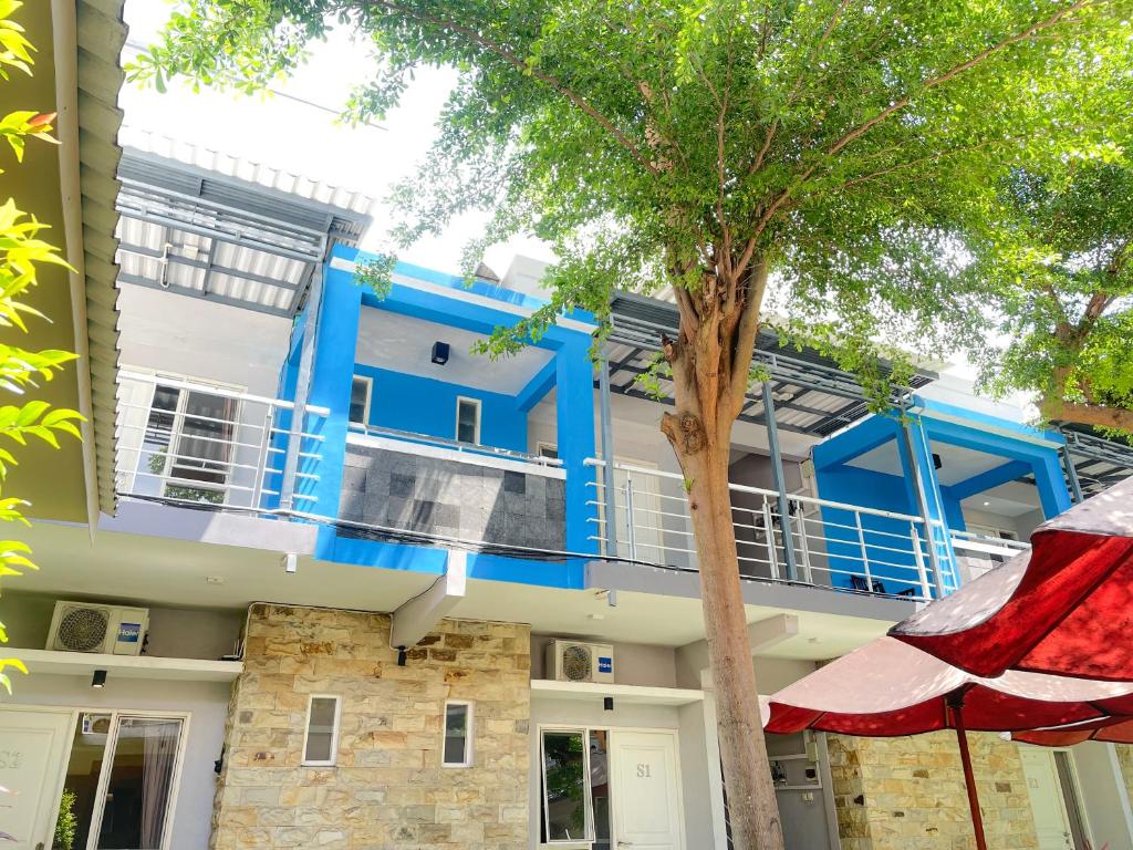 a blue building with a tree in front of it at Hotel O Kate'el Inn in Banyuwangi
