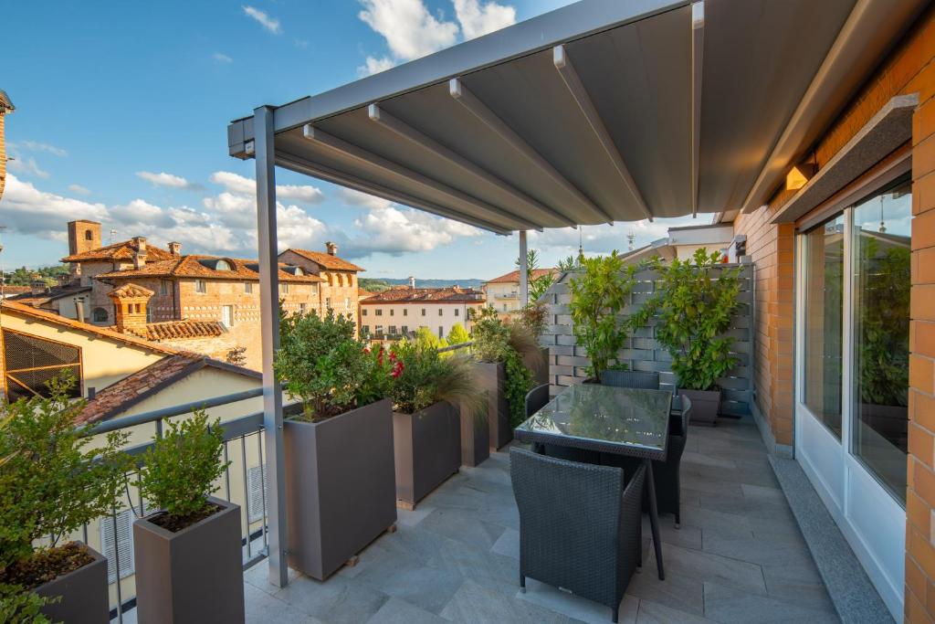 a patio with a table and chairs on a balcony at Attico Centrale Piazza Pertinace free parking in Alba