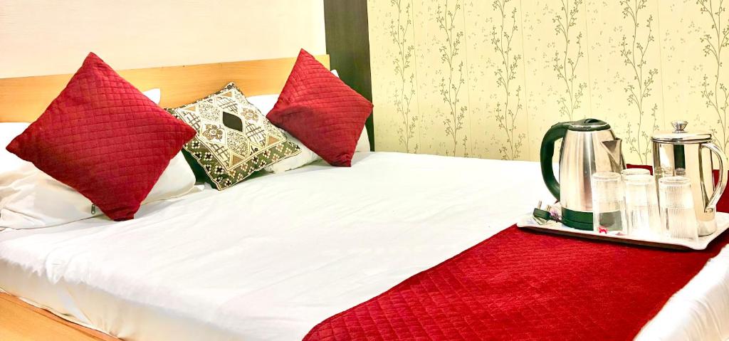 バラナシにあるKashi vishweshwar home stayの赤い枕と水差しが置かれたベッド