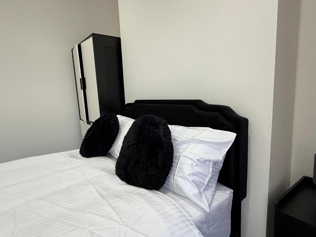 a white bed with two black fuzzy pillows on it at The Clare Court 6BR Luxury Retreat - Sleeps 14 with Complimentary Access to Billing Aquadrome Holiday Village for Swimming - 2 nights minimum in Kingsthorpe