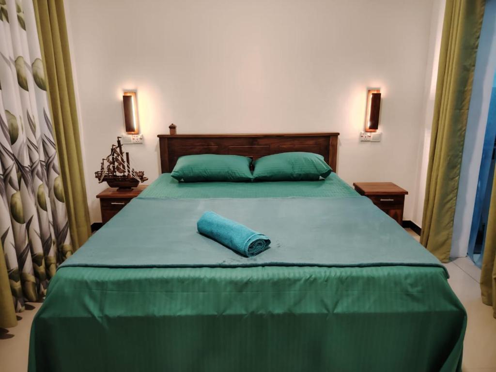 a large green bed with a blue pillow on it at Yesumishi Airport Villas - Transit Hotel Katunayake in Seeduwa