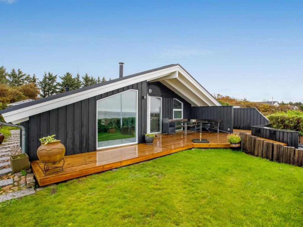 a small house with a deck and a yard at Holiday Home Holmwith - 50m from the sea by Interhome in Esbjerg