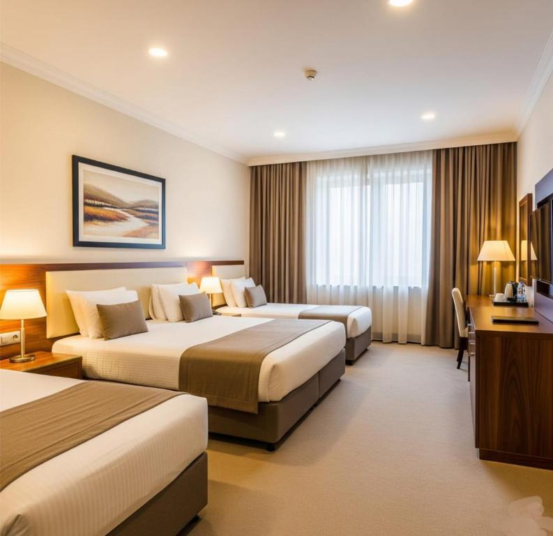 a hotel room with two beds and a desk at Khatai Family Hotel & Restaurant in Baku