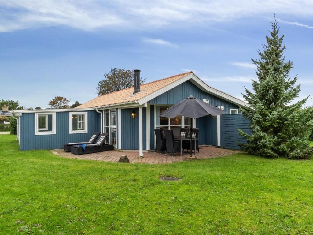 a blue house with a patio and an umbrella at Holiday Home Kjera - 450m from the sea by Interhome in Hadsund