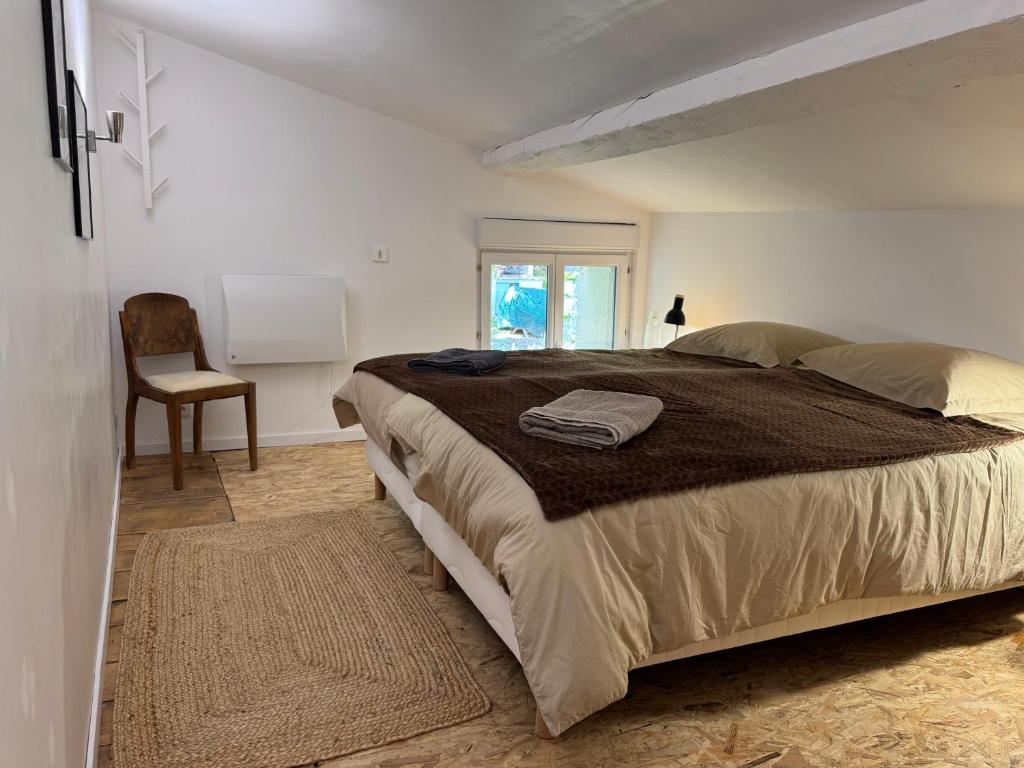 ein Schlafzimmer mit einem großen Bett und einem Stuhl in der Unterkunft Proche Carcassone chambre avec salle de bain et WC privée Piscine salon et kitchenette partagés avec voyageurs in Cépie