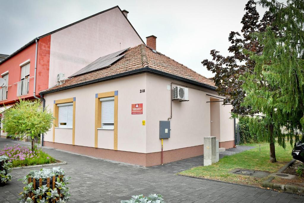 a small white building with a pitched roof at Tömörkény utcai vendégház in Mórahalom