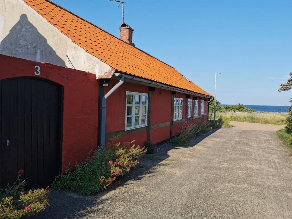 a red building with an orange roof and a driveway at Holiday Home Elvira - 300m from the sea by Interhome in Svaneke