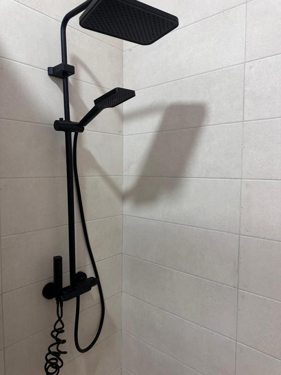 a shower with a black shower head in a bathroom at Bratti's Apartment 2 Near Tirana Center And Mother Teresa International Airport in Laknas