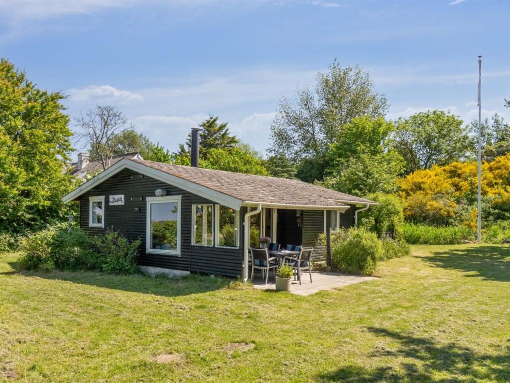 une petite maison noire avec une terrasse couverte et une cour dans l'établissement Holiday Home Benthe - 200m from the sea by Interhome, à Humble
