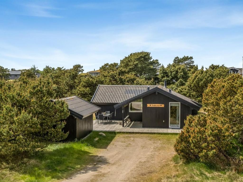 a black house with a dirt road in front of it at Holiday Home Ubbe - 800m from the sea by Interhome in Fanø
