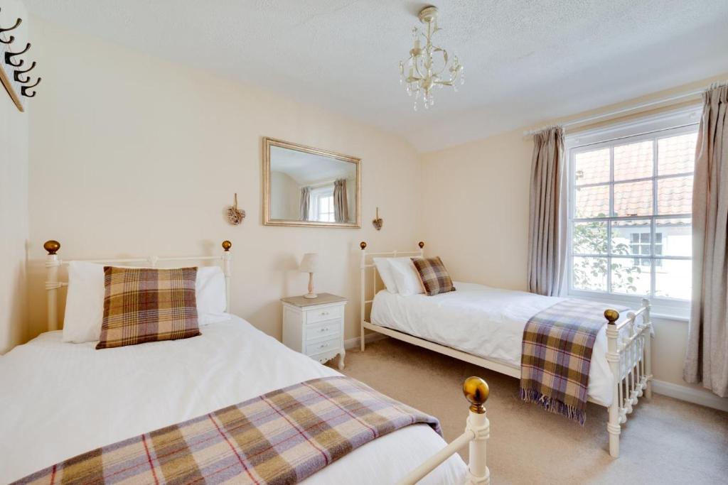 1 Schlafzimmer mit 2 Betten, einem Spiegel und einem Fenster in der Unterkunft Twitten Cottage in Southwold