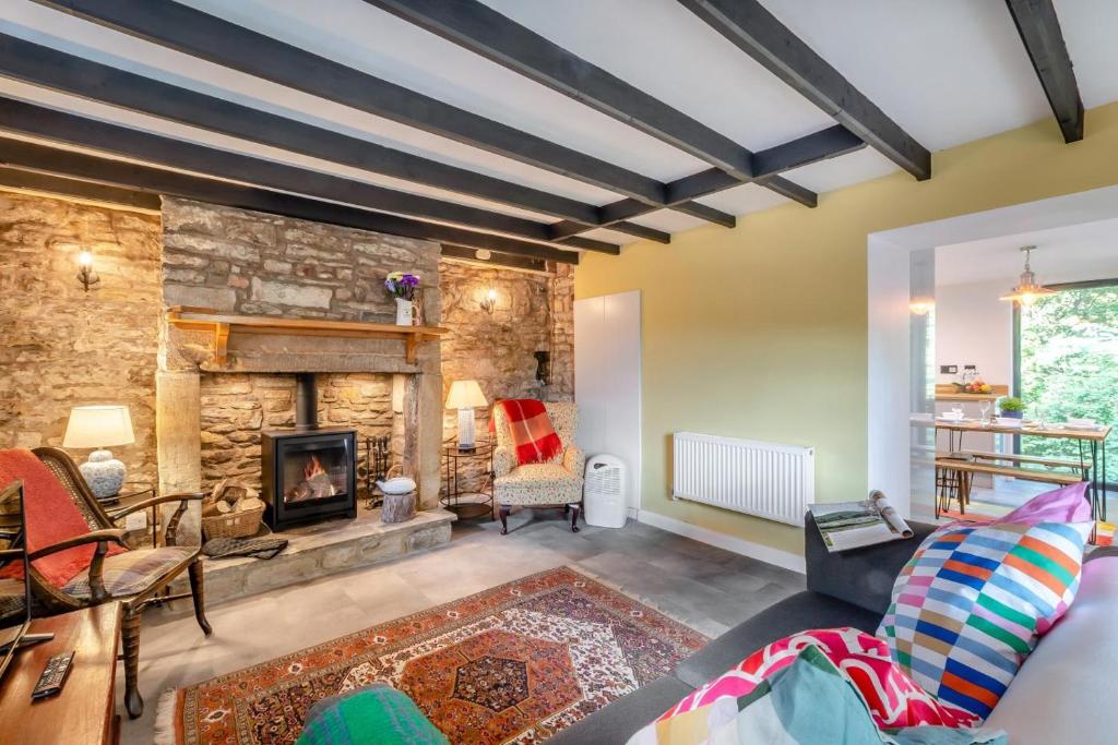 Bankside Cottage في هالتويسل: غرفة معيشة مع جدار حجري ومدفأة