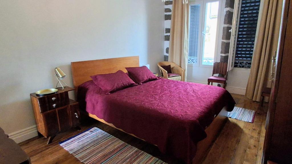 a bedroom with a large bed with a purple blanket at Arruda´s House in Ponta Delgada