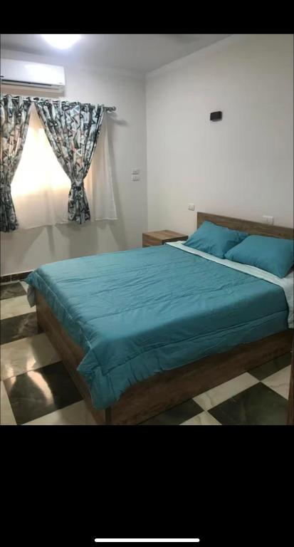 a bedroom with a bed with blue sheets and a window at Dream Apartment 4 in Hurghada