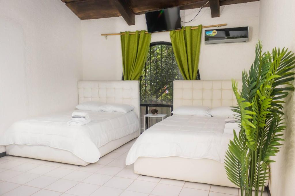 two beds in a room with green curtains at Hotel Casona del Valle in Potrerillos