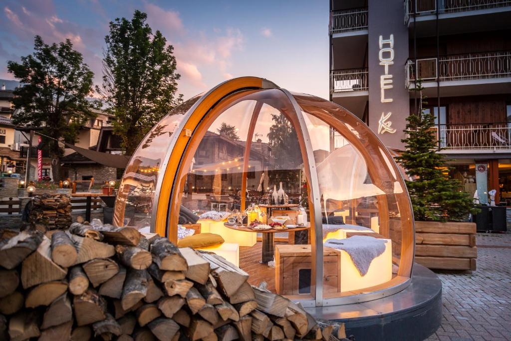 ein Kuppelgebäude mit einem Tisch und Stühlen und einem Stapel Holz in der Unterkunft Hotel K2 in Sauze dʼOulx