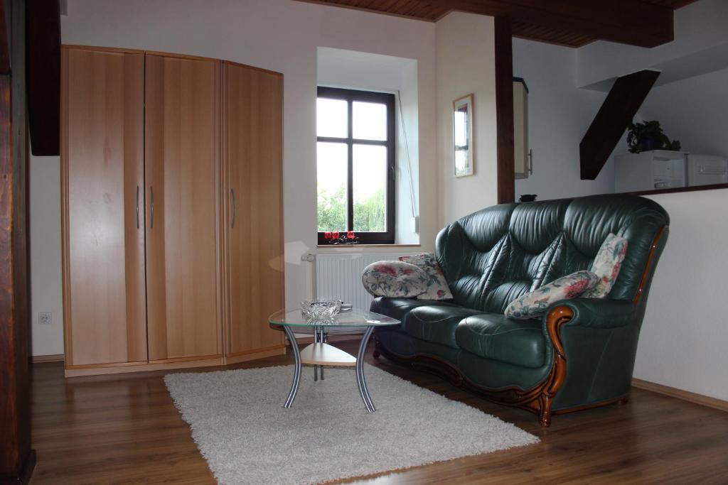 ein Wohnzimmer mit einem grünen Ledersofa und einem Tisch in der Unterkunft Ferienwohnung Prenzlau in Prenzlau