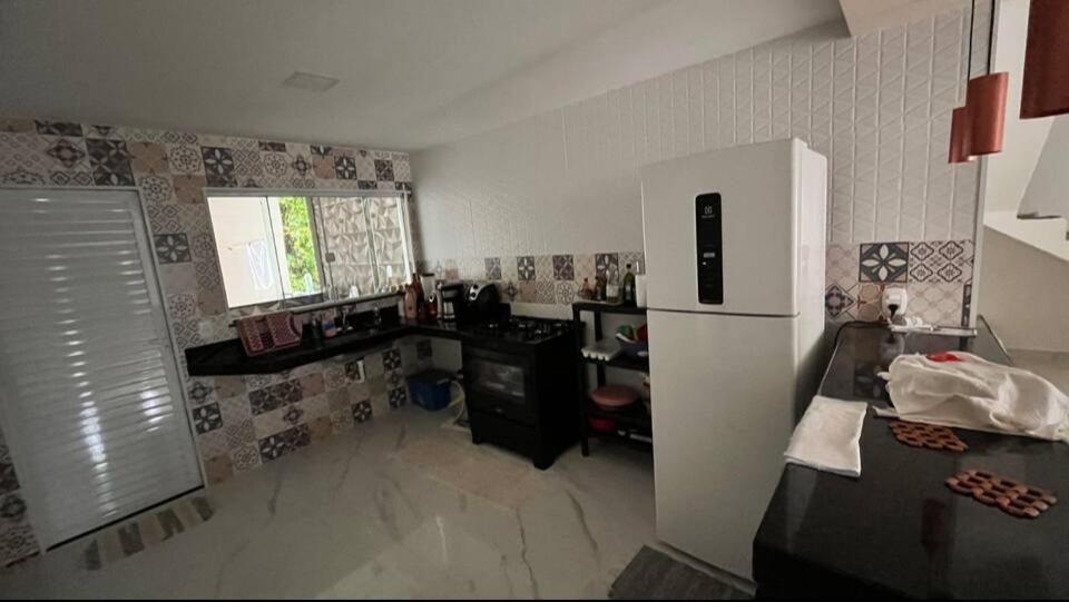 a kitchen with a refrigerator and a table in it at Casa para temporada Balneário de IRIRI Espírito Santo ES in Iriri