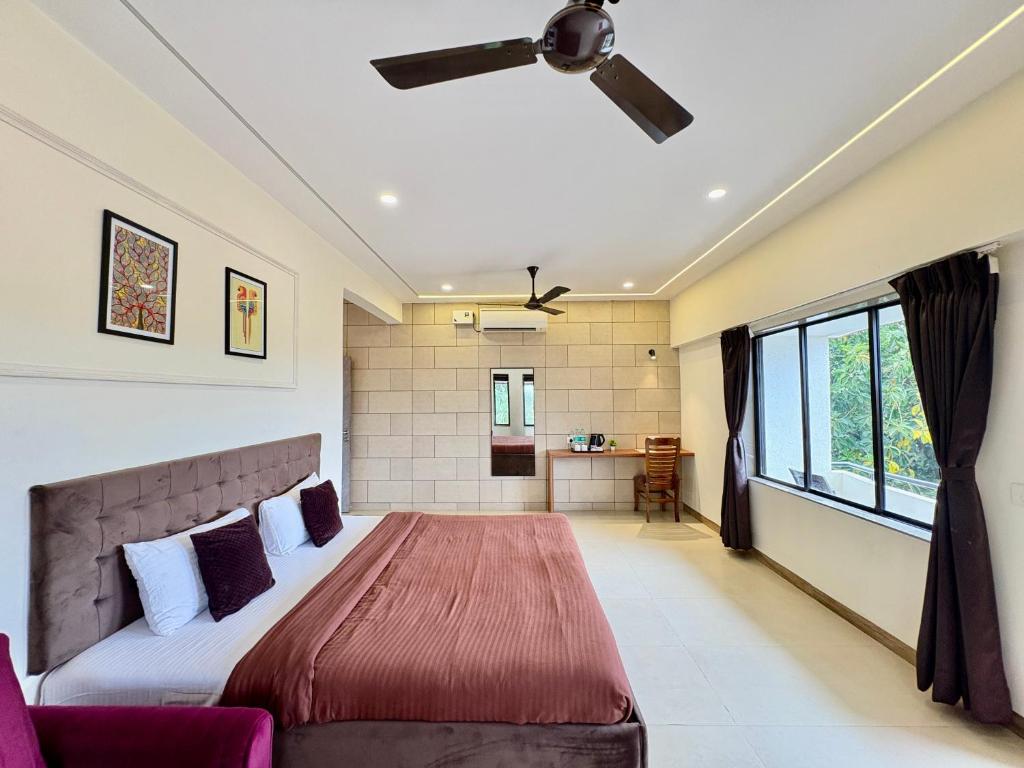 a bedroom with a bed and a ceiling fan at Girivihar Holiday Club - Pure Veg in Lonavala