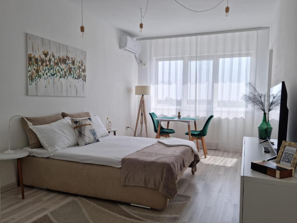 a bedroom with a bed and a table with chairs at Studio Nova - Minimalist and Elegant with Parking in Bucharest
