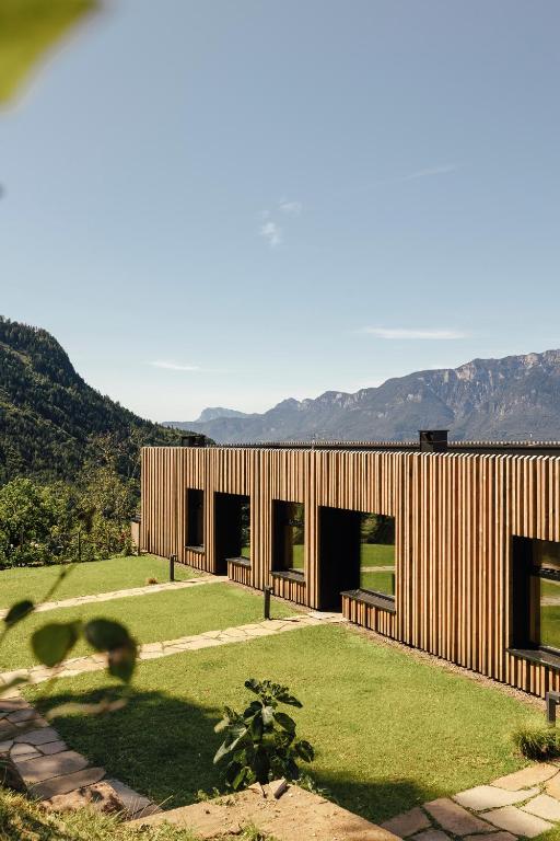 a wooden house with a large yard with grass at Hochegg Hideaway in Laives