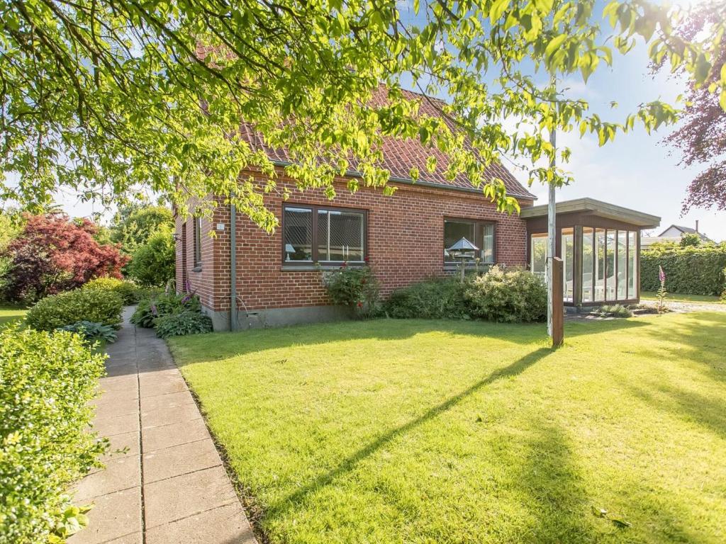 a red brick house with a grass yard at Holiday Home Sakulf - 500m from the sea by Interhome in Sæby