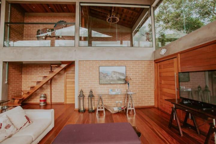 a living room with a staircase and a couch at Chalet nas Nuvens with Infinity Pool in São Bento do Sapucaí