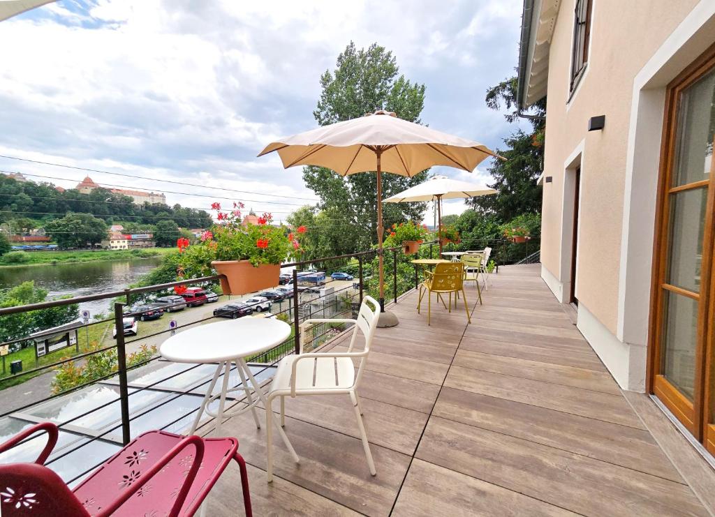 a balcony with chairs and tables and an umbrella at Ferienwohnung Villa 16F in Pirna