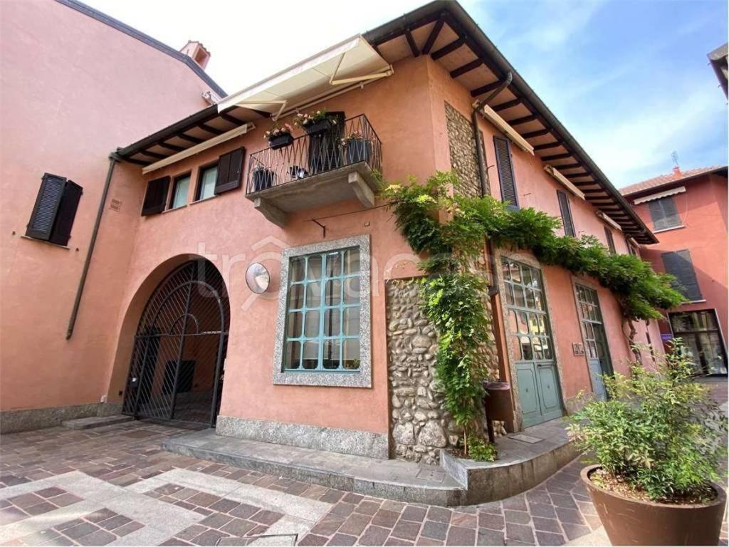 ein rosafarbenes Gebäude mit nebenstehenden Pflanzen in der Unterkunft Domus Eleonora tra Laghi e Malpensa MXP in Sesto Calende