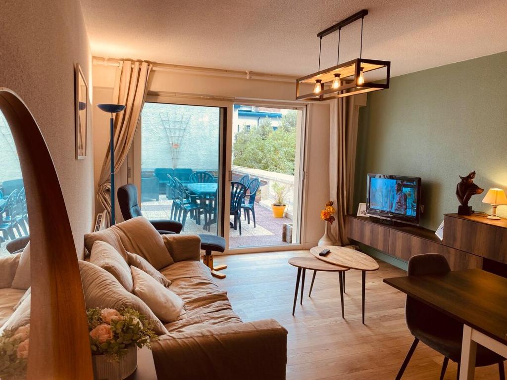 a living room with a couch and a dining room at Le Louisiane in Le Touquet-Paris-Plage
