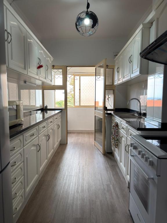 a large kitchen with white cabinets and black counter tops at Ohana Funchal in Funchal