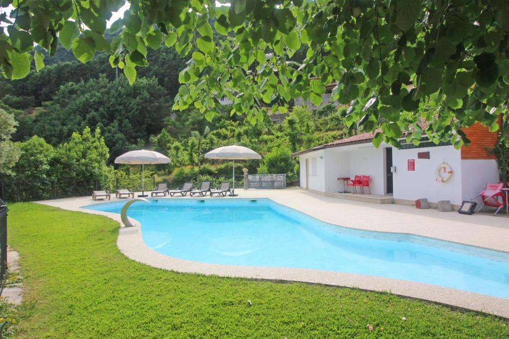 einen Pool im Garten mit Stühlen und Sonnenschirmen in der Unterkunft Casas da Paz by Gerês Casas in Geres