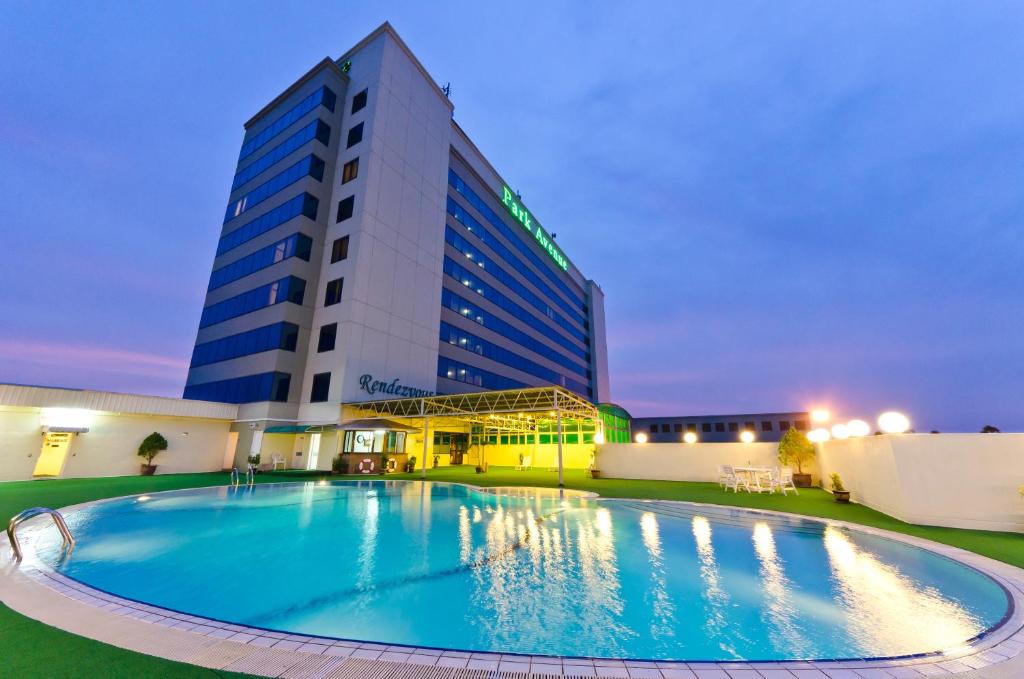 a hotel with a large swimming pool in front of a building at Park Avenue Hotel Sungai Petani in Sungai Petani