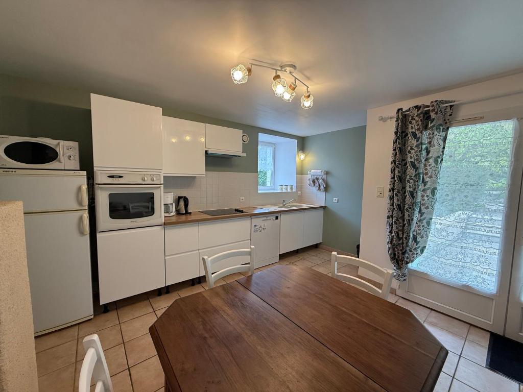 a kitchen with white appliances and a wooden table at Domaine du Thie in Dirac