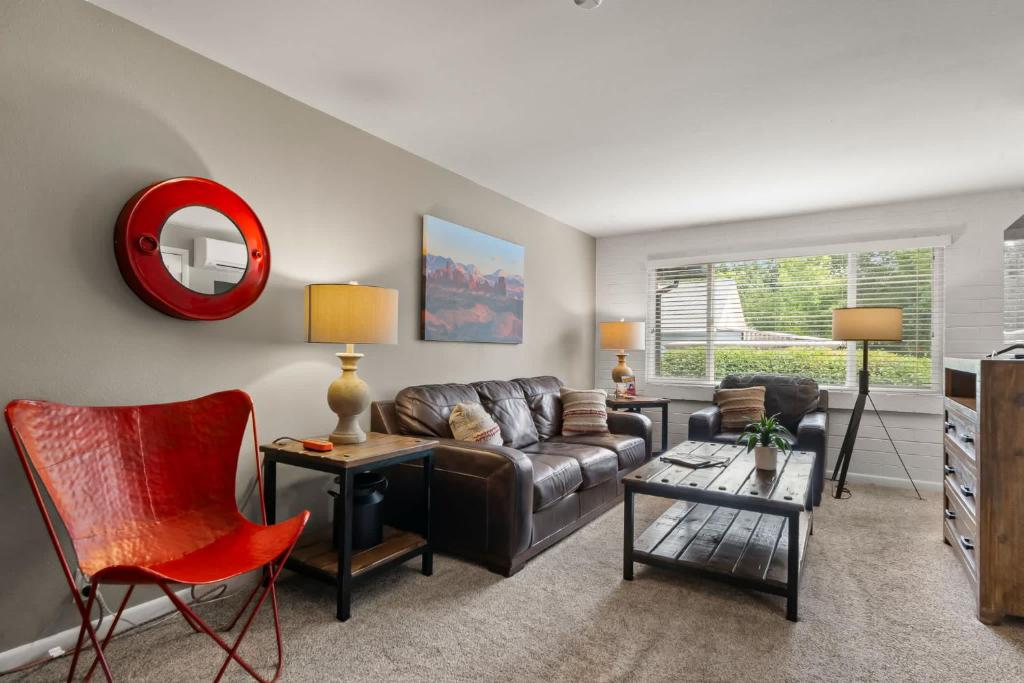 a living room with a leather couch and a red chair at Downtown Cozy Home Base - Purple Sage 7 in Moab