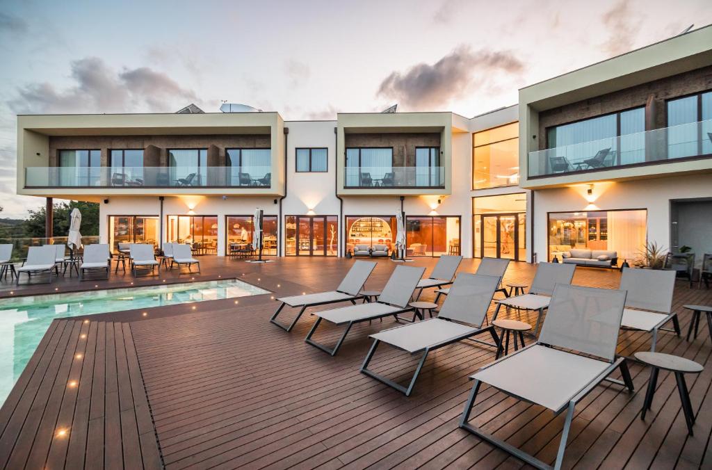 a building with a deck with chairs and a pool at Haven Nature Hotel & Villas in Batalha
