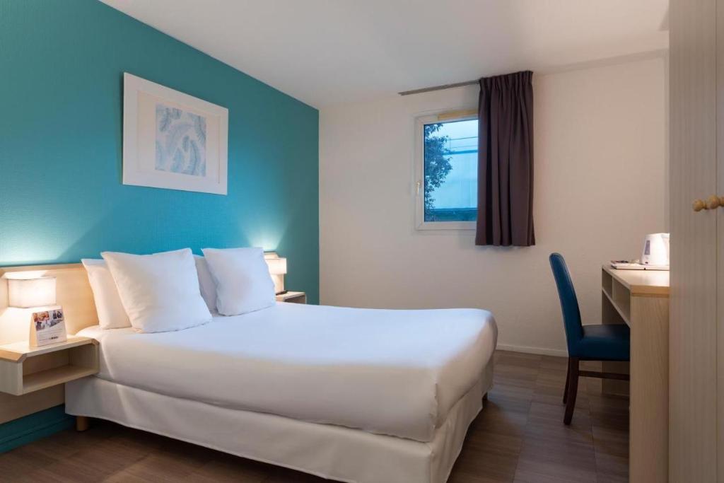 a hotel room with a large bed and a desk at Comfort Hotel Orleans Saran in Saran