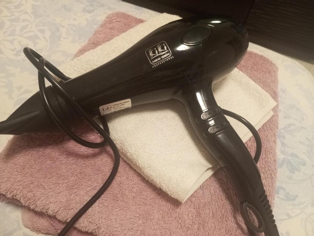 a black hair dryer sitting on top of a towel at Room Flower Near Airport in Ariana